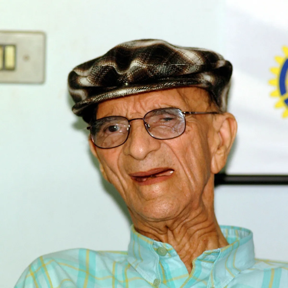 Chico Xavier sorridente, usando boina, em fotografia de 2002