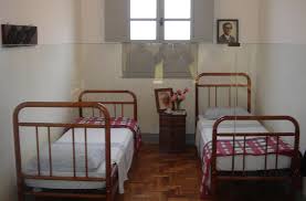 Quarto simples de Chico Xavier em Pedro Leopoldo, com camas de ferro e seu retrato na parede