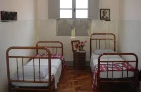 Quarto simples de Chico Xavier em Pedro Leopoldo, com camas de ferro e seu retrato na parede